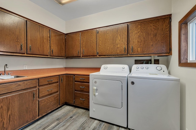 laundry area featuring cabinets, independent washer and dryer, light hardwood / wood-style floors, and sink