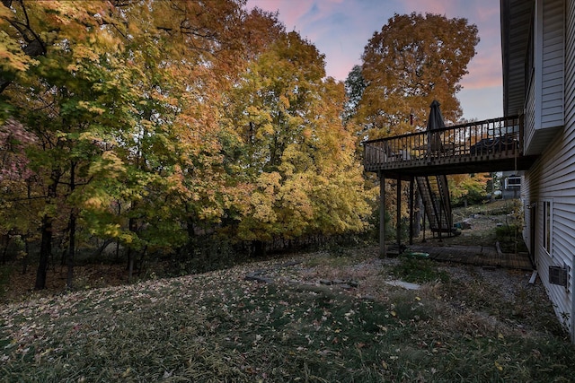 yard at dusk featuring a deck and stairway