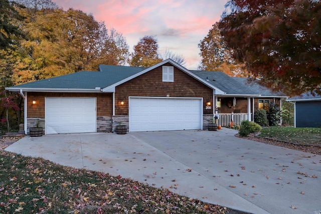 view of front facade with a garage, stone siding, driveway, and a porch