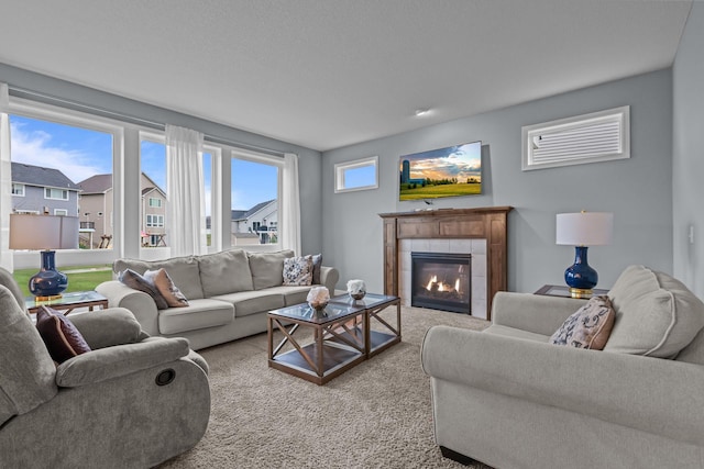 carpeted living area featuring a tiled fireplace