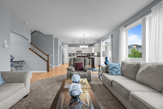 living room with baseboards, stairway, light wood-type flooring, recessed lighting, and a notable chandelier