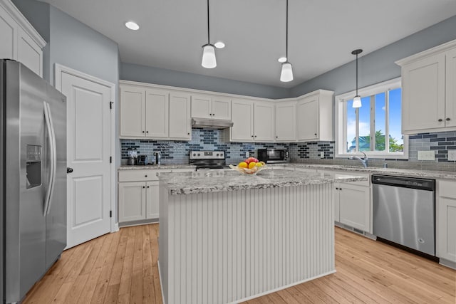 kitchen featuring under cabinet range hood, appliances with stainless steel finishes, tasteful backsplash, and light wood-type flooring