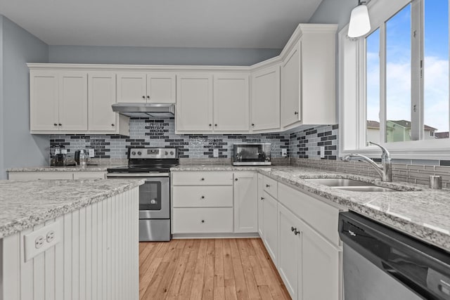 kitchen featuring appliances with stainless steel finishes, a sink, white cabinetry, backsplash, and under cabinet range hood