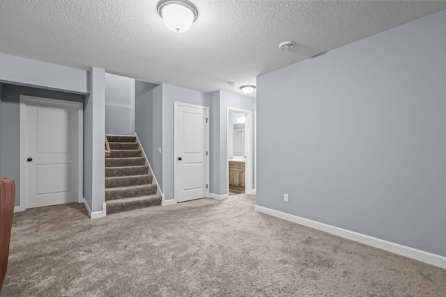below grade area with baseboards, carpet flooring, stairs, and a textured ceiling