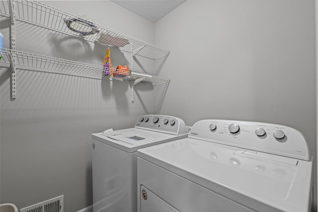 washroom featuring separate washer and dryer, laundry area, and visible vents