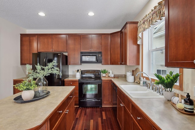 kitchen featuring dark wood-type flooring, light countertops, a textured ceiling, black appliances, and a sink