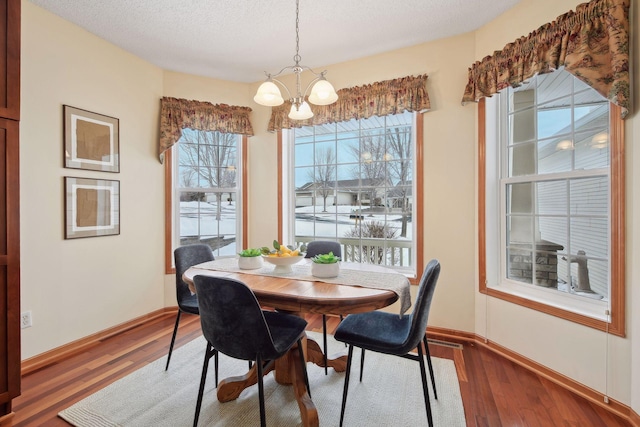 dining room with a textured ceiling, baseboards, wood finished floors, and an inviting chandelier