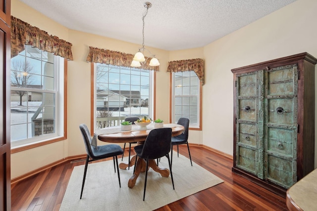 dining room featuring dark wood-style flooring, a notable chandelier, a textured ceiling, and baseboards