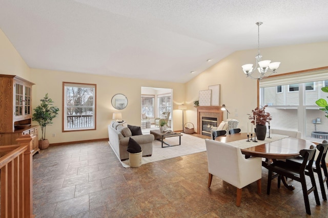 dining room featuring lofted ceiling, a textured ceiling, a chandelier, a fireplace with flush hearth, and baseboards