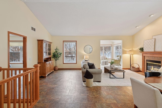 living room featuring high vaulted ceiling, a tile fireplace, visible vents, and baseboards