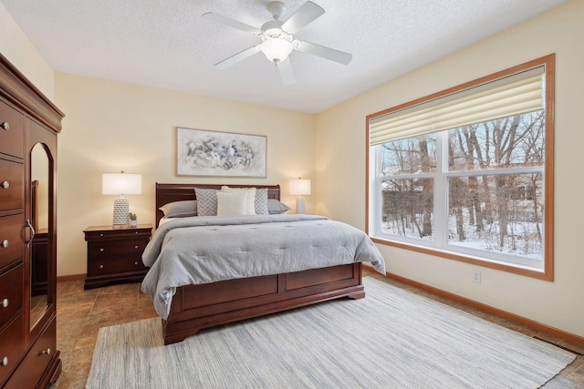 bedroom featuring a textured ceiling, ceiling fan, and baseboards