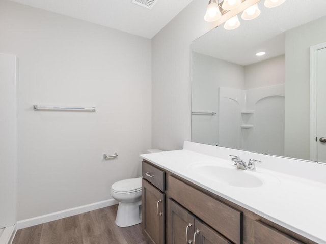 bathroom featuring hardwood / wood-style flooring, vanity, toilet, and a shower