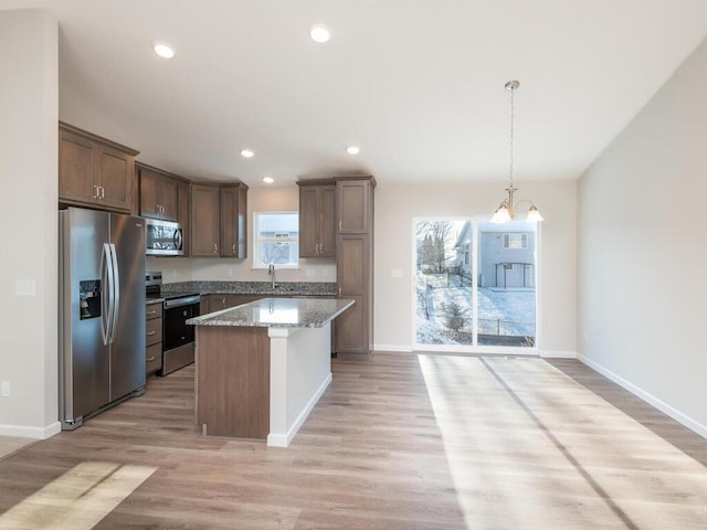 kitchen featuring stone counters, sink, light hardwood / wood-style flooring, a kitchen island, and stainless steel appliances