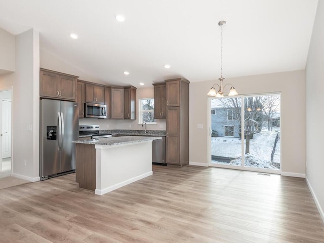 kitchen featuring decorative light fixtures, an inviting chandelier, stainless steel appliances, and light hardwood / wood-style flooring