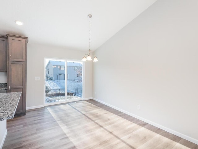 unfurnished dining area featuring light hardwood / wood-style floors and an inviting chandelier