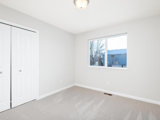 unfurnished bedroom with light carpet and a closet