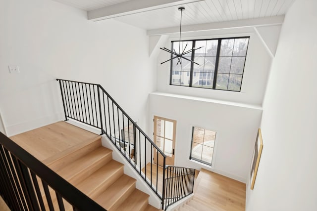 stairs featuring a chandelier, lofted ceiling with beams, hardwood / wood-style flooring, and wood ceiling