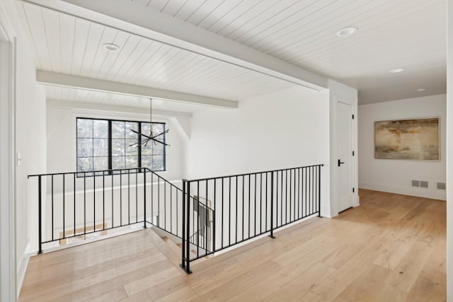 hallway with beamed ceiling, hardwood / wood-style floors, wooden ceiling, and a notable chandelier