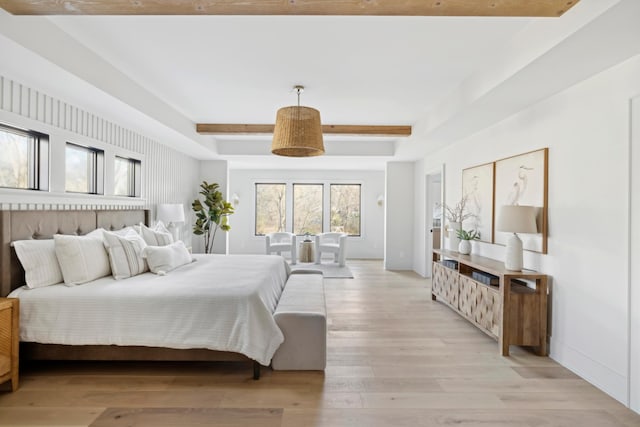 bedroom featuring beamed ceiling and light wood-type flooring