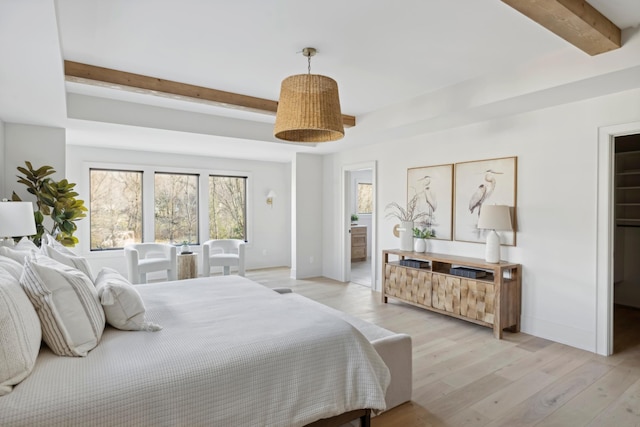 bedroom with light hardwood / wood-style floors, beam ceiling, and ensuite bath