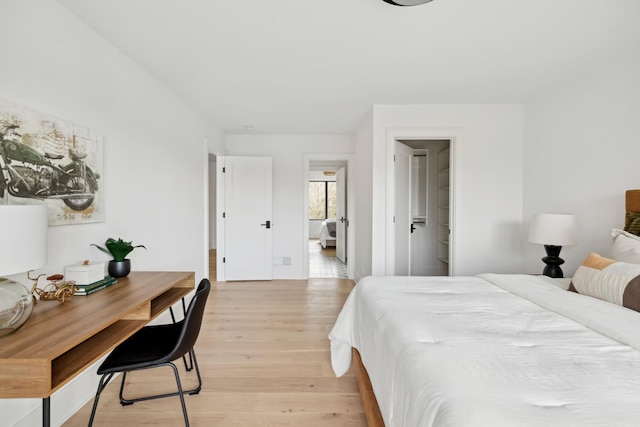 bedroom with ensuite bathroom and light hardwood / wood-style floors