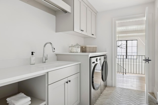 laundry room featuring cabinets, sink, washer and dryer, and light hardwood / wood-style floors