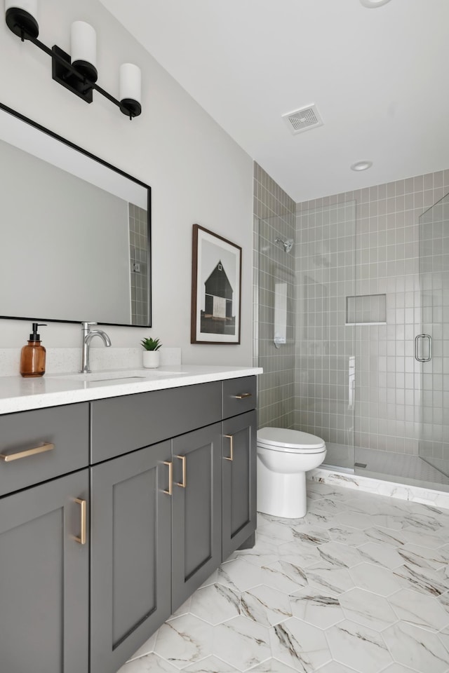 bathroom featuring vanity, toilet, and a shower with shower door