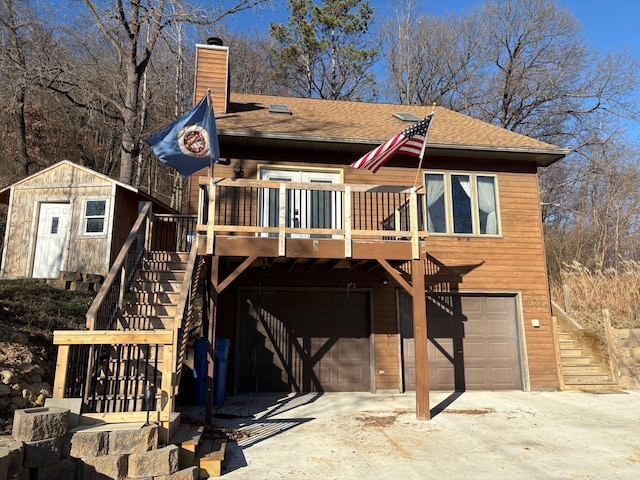 view of front of home featuring a wooden deck, a storage unit, and a garage