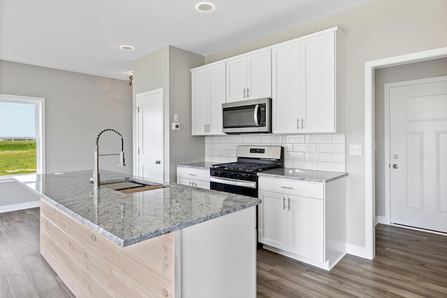 kitchen featuring white cabinets, appliances with stainless steel finishes, sink, and an island with sink