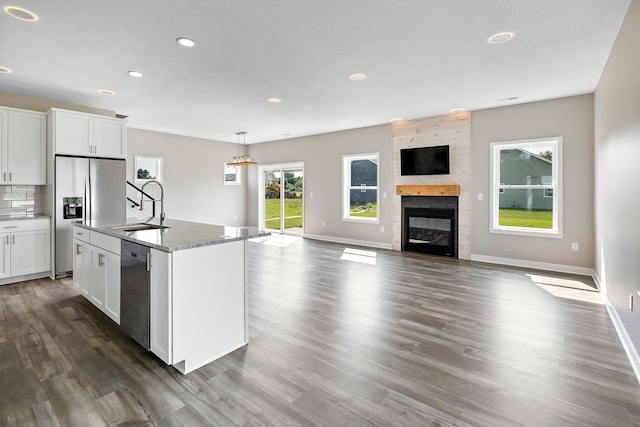 kitchen with a center island with sink, sink, a fireplace, appliances with stainless steel finishes, and white cabinetry