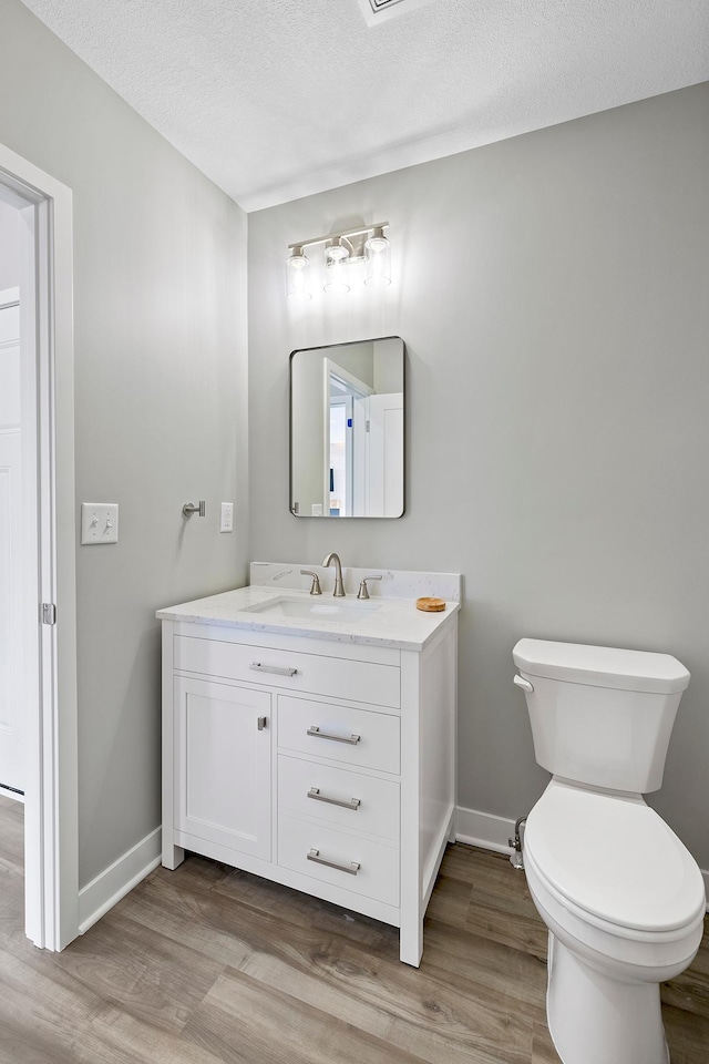 bathroom featuring vanity, wood-type flooring, a textured ceiling, and toilet