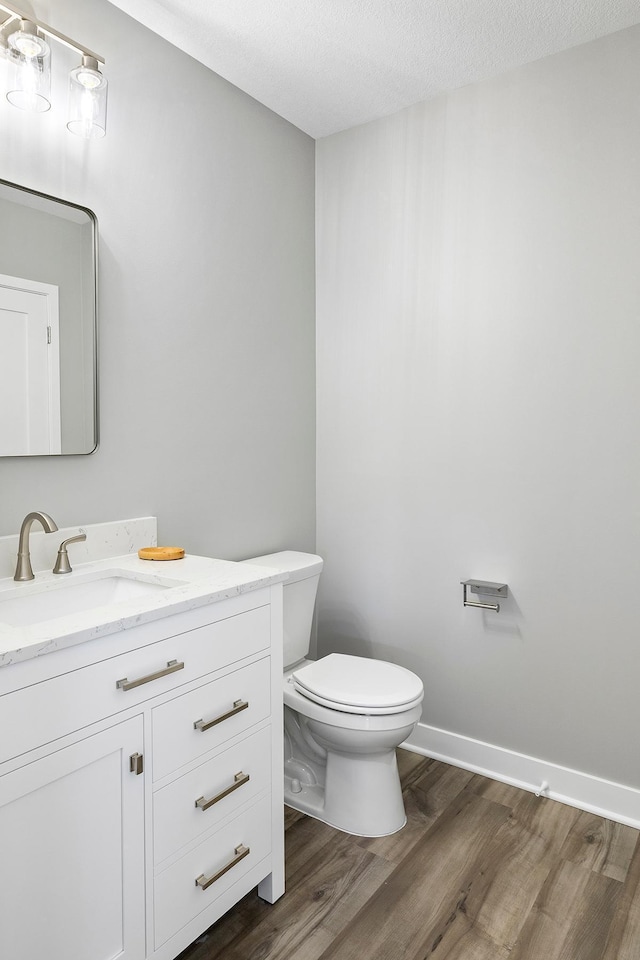 bathroom featuring hardwood / wood-style flooring, vanity, toilet, and a textured ceiling