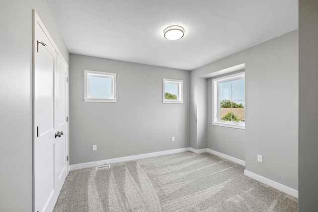 carpeted empty room featuring a textured ceiling