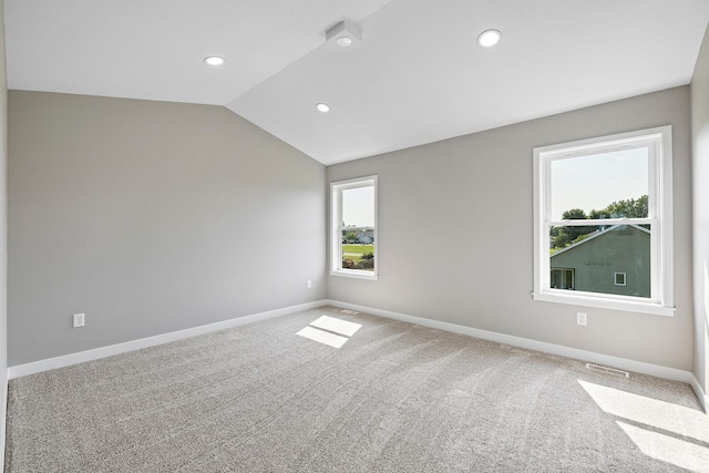 carpeted empty room featuring plenty of natural light and lofted ceiling