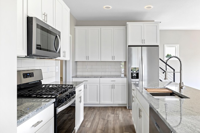 kitchen with white cabinetry, sink, stainless steel appliances, light stone counters, and light hardwood / wood-style flooring