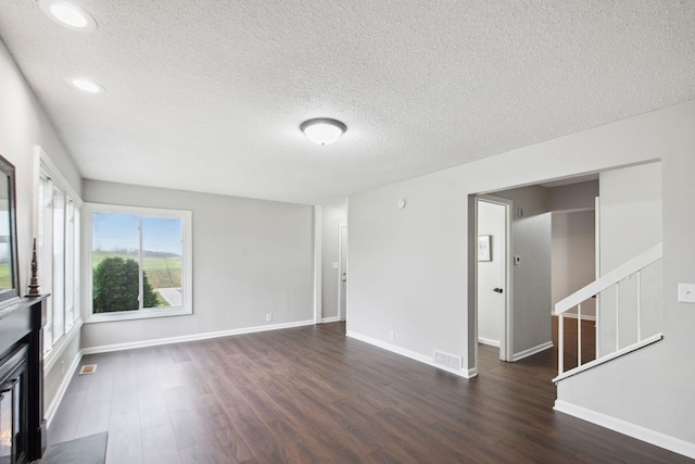 unfurnished living room featuring a textured ceiling and dark hardwood / wood-style floors