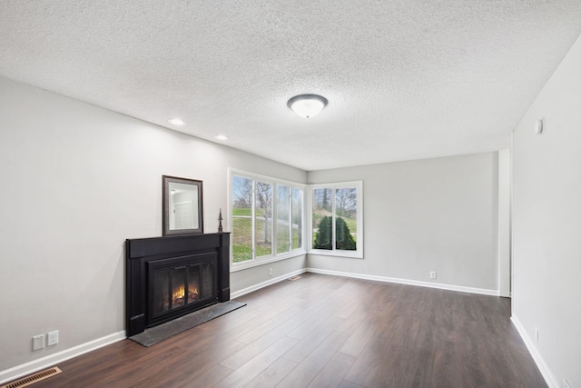 unfurnished living room featuring dark hardwood / wood-style flooring and a textured ceiling