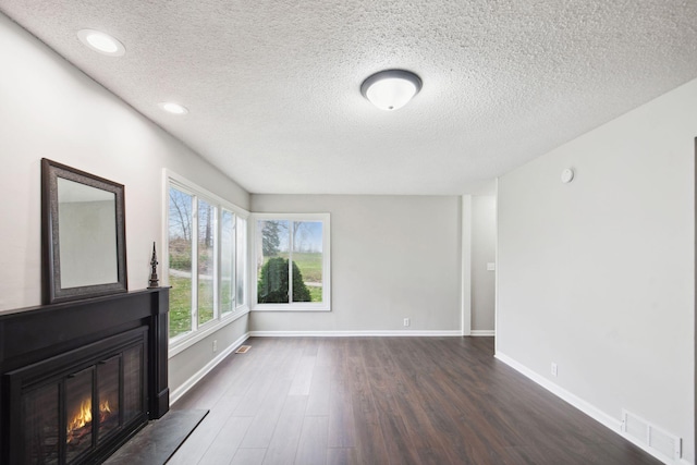 spare room featuring a textured ceiling and dark hardwood / wood-style flooring