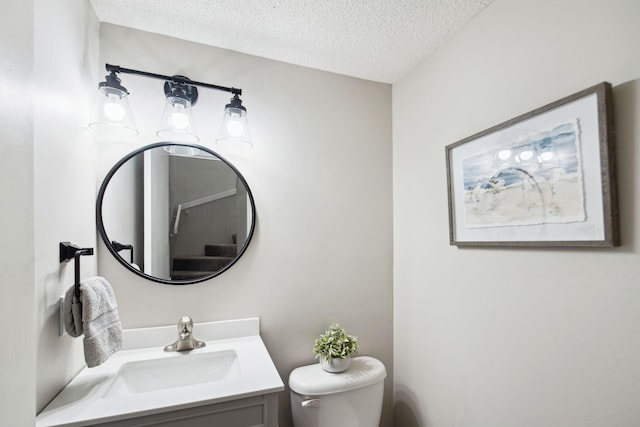 bathroom featuring vanity, a textured ceiling, and toilet