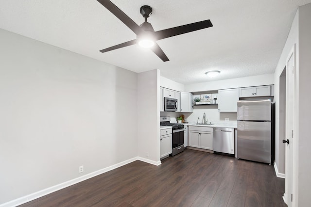 kitchen featuring a textured ceiling, stainless steel appliances, ceiling fan, dark wood-type flooring, and sink