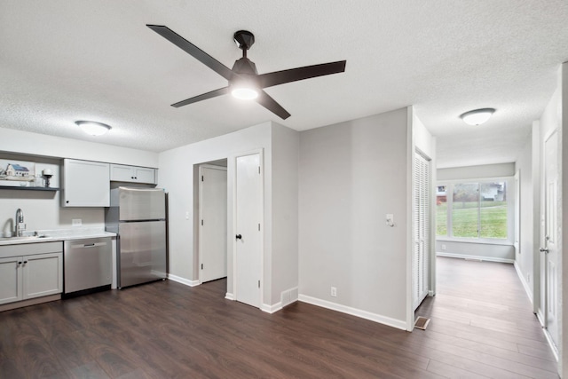 kitchen featuring sink, ceiling fan, a textured ceiling, appliances with stainless steel finishes, and dark hardwood / wood-style flooring