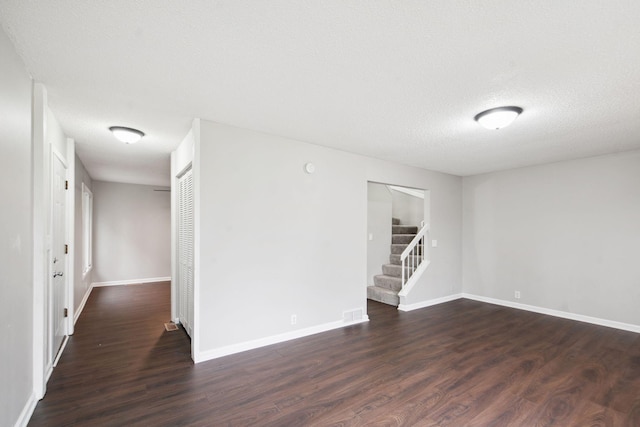 spare room with a textured ceiling and dark wood-type flooring