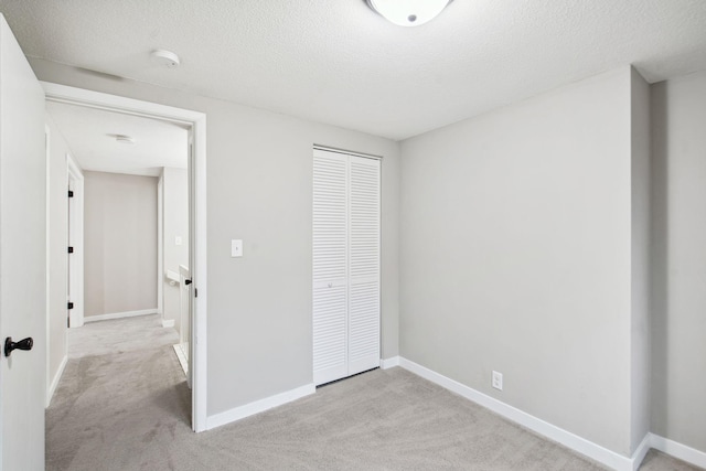 unfurnished bedroom featuring light carpet, a closet, and a textured ceiling