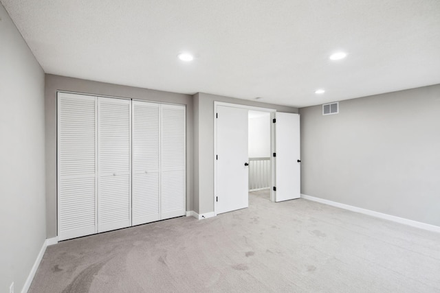 unfurnished bedroom featuring light carpet and a closet