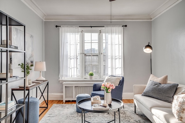 sitting room with hardwood / wood-style floors, radiator heating unit, and ornamental molding