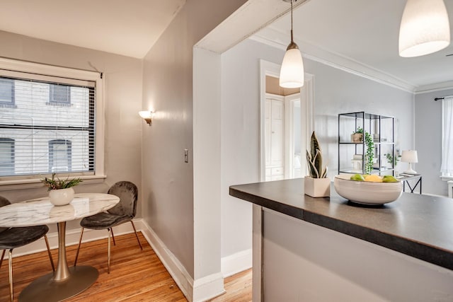 kitchen featuring light wood-type flooring, decorative light fixtures, and ornamental molding