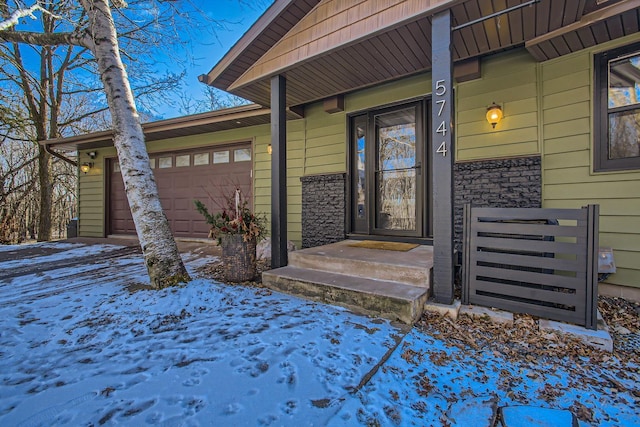 snow covered property entrance with a garage