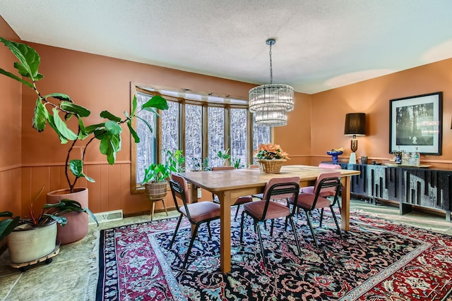 dining room featuring visible vents, a chandelier, a textured ceiling, and wainscoting