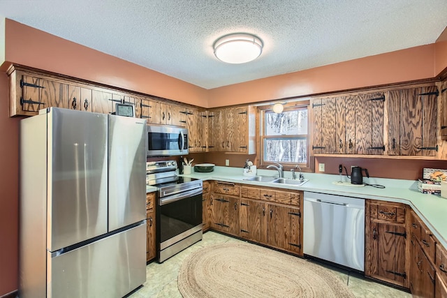 kitchen featuring stainless steel appliances, light countertops, a sink, and a textured ceiling