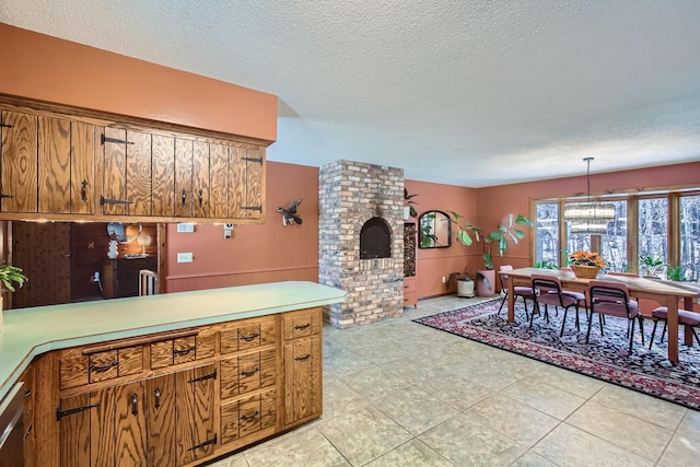 kitchen featuring light tile patterned floors, brown cabinets, light countertops, a textured ceiling, and pendant lighting